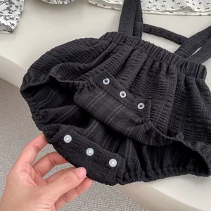 Détail d'un barboteuse bébé en seersucker noir avec trois boutons-pression à l'entrejambe