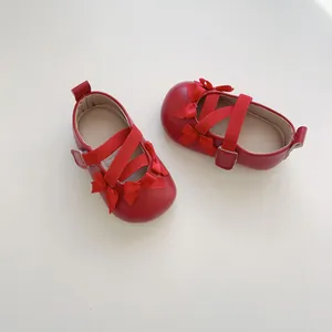 Dettaglio scarpe neonato rosse con fiocchi di seta e chiusura a strappo in velcro