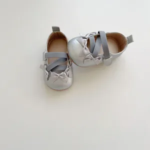 Dettaglio scarpe bimbo argento con fiocchi in seta e cinturini elastici incrociati