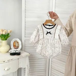 Detailed view of floral baby romper featuring delicate lace ruffles and black bows