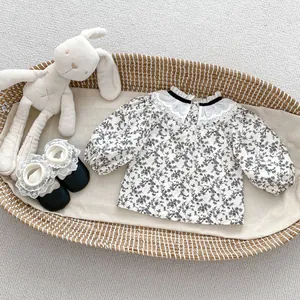 Détail d'un chemisier fleuri pour bébé avec col en dentelle double et ruban noir chic