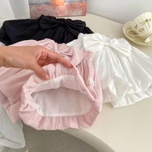 Detail of baby cotton bloomers with large bow decoration in black, white, and pink