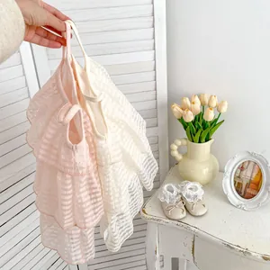 Detail rosa Rüschen am Baby-Sommerkleid mit weißer Schleife und gestreifter Stoffstruktur