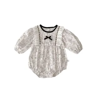 Floral baby bodysuit with long sleeves, lace shoulders, and a black bow accent