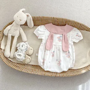 Detail of infant bodysuit with bunny ear collar and bear print in a woven basket