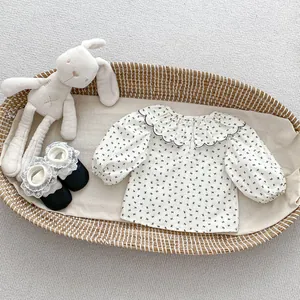 Détail d'un chemisier bébé fille à imprimé nœuds, col volanté et chaussures en dentelle