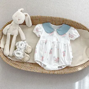 Flat lay of white baby bodysuit with blue collar and cute bear print in basket