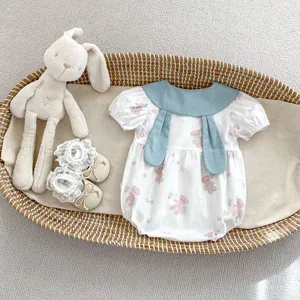 Detail of baby summer bodysuit with bear print, bunny ear collar and lace shoes