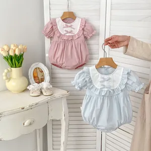 Détail de barboteuses bébé avec cols à volants et nœuds en rose et bleu pastel