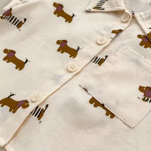 Dettaglio di camicia in cotone per neonati con stampe di bassotto e bottoni beige