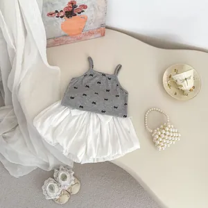 Detail of baby girl summer set featuring a bow printed grey top and white puff shorts