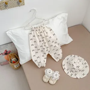 Detailed set of cream baby bodysuit with black bows, matching sun hat and lace shoes
