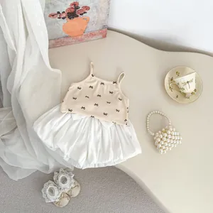 Detailed flat lay of toddler summer set with bow strap top and white bloomers