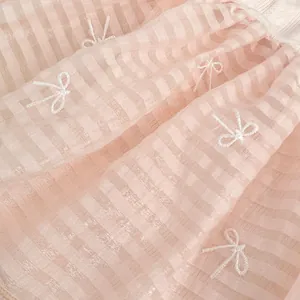 Close-up of baby girl pink mesh dress fabric with cute embroidered white bows