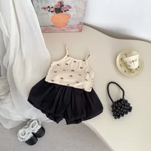 Flat lay of girl's summer outfit with bow print camisole and black balloon shorts