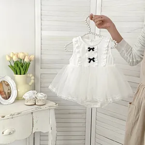 Detail of white mesh baby dress with velvet bows on a pearl hanger with lace shoes