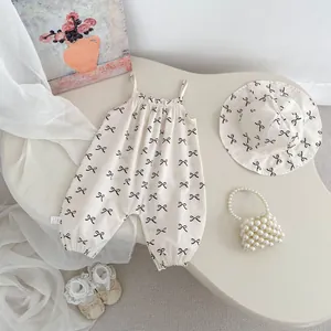 Flat lay of cream baby romper and sun hat set with black bow patterns and lace shoes