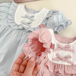 Détail de la barboteuse pour bébé montrant dentelle, nœuds et manches à volants en coton doux