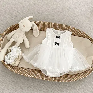 Detail of white infant sleeveless mesh romper dress with black bows in a wicker basket
