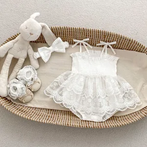 Détail d'un ensemble bébé en dentelle blanche avec bandeau assorti et chaussons à fleurs