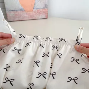 Detail of baby bodysuit featuring black bow patterns and delicate elastic neckline craftsmanship
