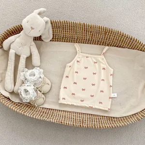 Detail view of beige ribbed baby tank top with red bow prints and size 66 label