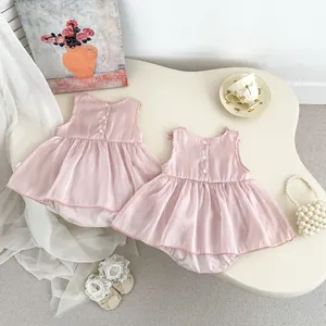 Detailed back view of pink satin baby dress with three white buttons and bow detail