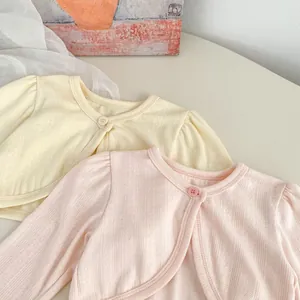 Close-up of lightweight hollow knit baby cardigans in beige and pink shades