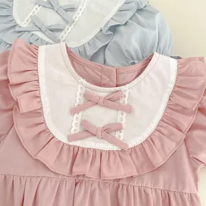 Détail d'un barboteuse bébé avec col à volants, dentelle et nœuds en rose et bleu pastel