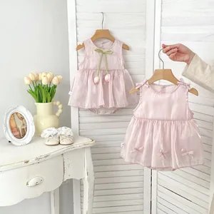 Detail of pink baby romper dresses with floral tulip accents and cute bow decorations