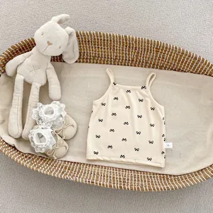 Detail of baby girl camisole with bow print and size tag in a woven basket