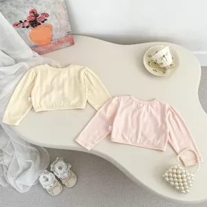 Flat lay of soft knit cotton infant cardigans in cream yellow and baby pink colors