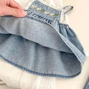Close-up of light blue denim fabric with floral embroidery and white lace trim