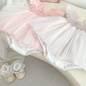 Flat lay of baby ruffle sleeve mesh onesie dresses with matching lace infant shoes