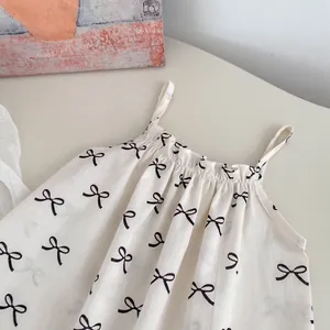 Close-up of baby bodysuit with black bow patterns and ruffled neckline detail