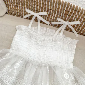 Détails de robe bébé fille avec buste froncé et dentelle brodée de fleurs