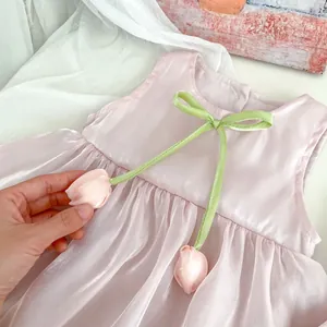 Detail of pink baby dress with green ribbon bow and 3D tulip fabric flower accents