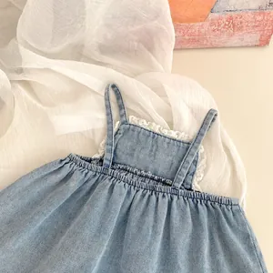 Detailed close-up of girls denim camisole top with white lace trim and pleated hem