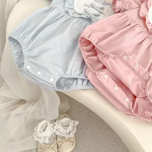 Détail de bodies bébé pastel avec cols à volants et boutons-pression pour le change