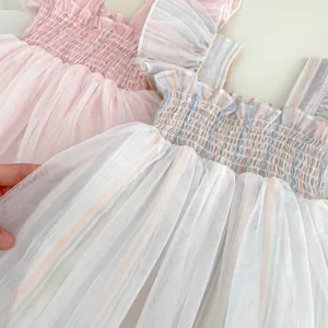 Detailed view of elastic smocked bodice and ruffled mesh straps on baby summer dresses