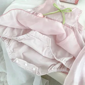 Detailed view of baby dress with green ribbon bow, tulip motif and bottom snap buttons