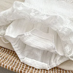 Détails de la barboteuse bébé en mousseline blanche avec bordure dentelle et boutons pressions
