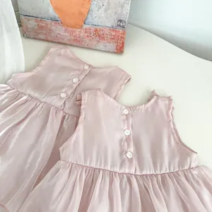 Detail view of pink infant dress back featuring three buttons and premium satin fabric