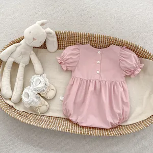 Barboteuse rose bébé à manches bouffantes et chaussures à nœuds dans un berceau