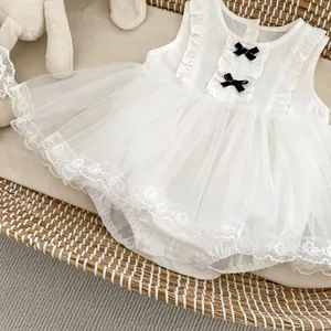 Detail view of white lace baby romper with black bows and soft tulle skirt layers