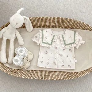 Detalle de la blusa floral para bebé con cuello de volantes verde salvia