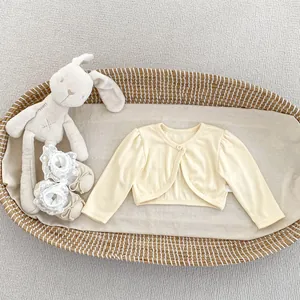 Detail of cream knit baby cardigan in a woven cradle, soft cotton mesh texture