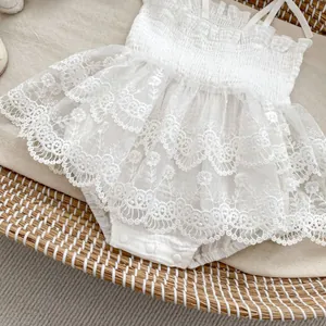 Détail d'une barboteuse en dentelle blanche pour bébé avec broderie florale et pressions