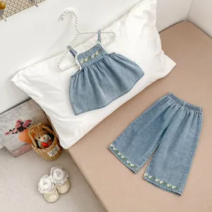Detail of girls denim set with ruffled top and embroidered yellow flower patches
