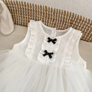 Detail of baby girl sleeveless tulle dress with ruffles and black bows on white fabric
